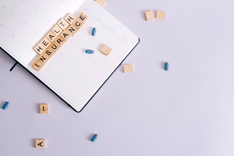 A flat lay showing a planner with 'health' written, along with medication pills and a stethoscope.